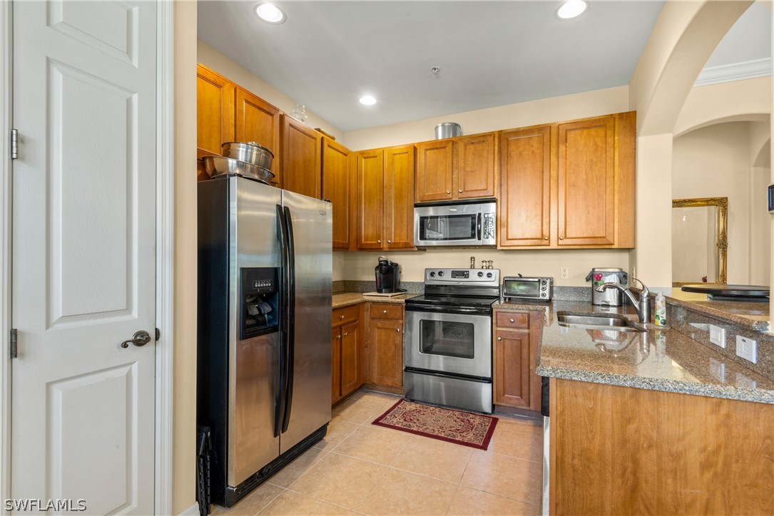 1387 Santiago Circle, Unit 802 Naples, FL 34113 - Photo 16 of 29 a kitchen with granite countertop a refrigerator stove and sink