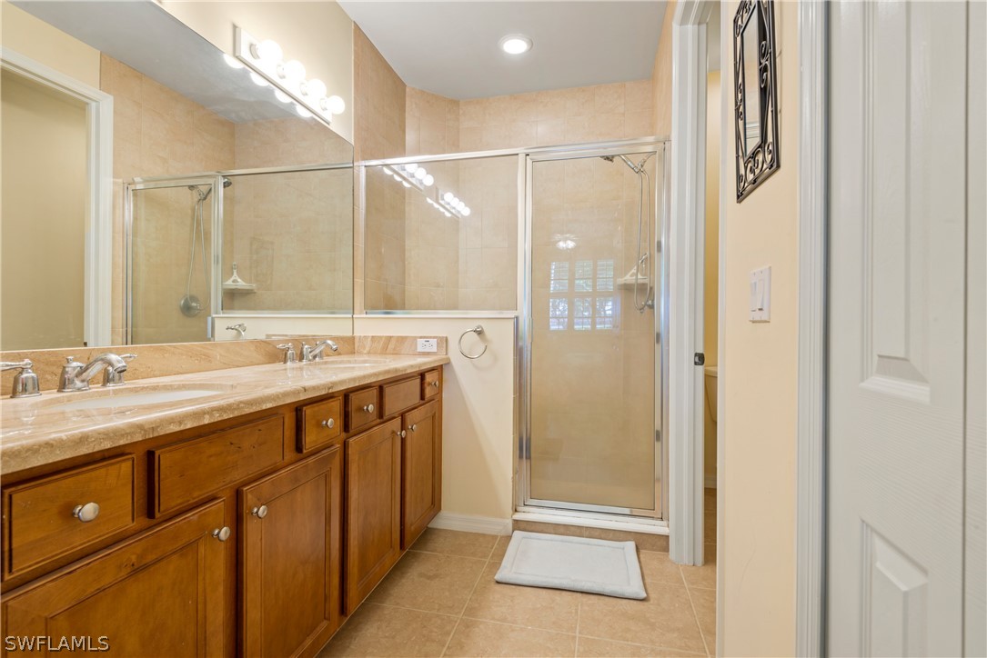 1387 Santiago Circle, Unit 802 Naples, FL 34113 - Photo 20 of 29 a bathroom with a double vanity sink a mirror and a shower
