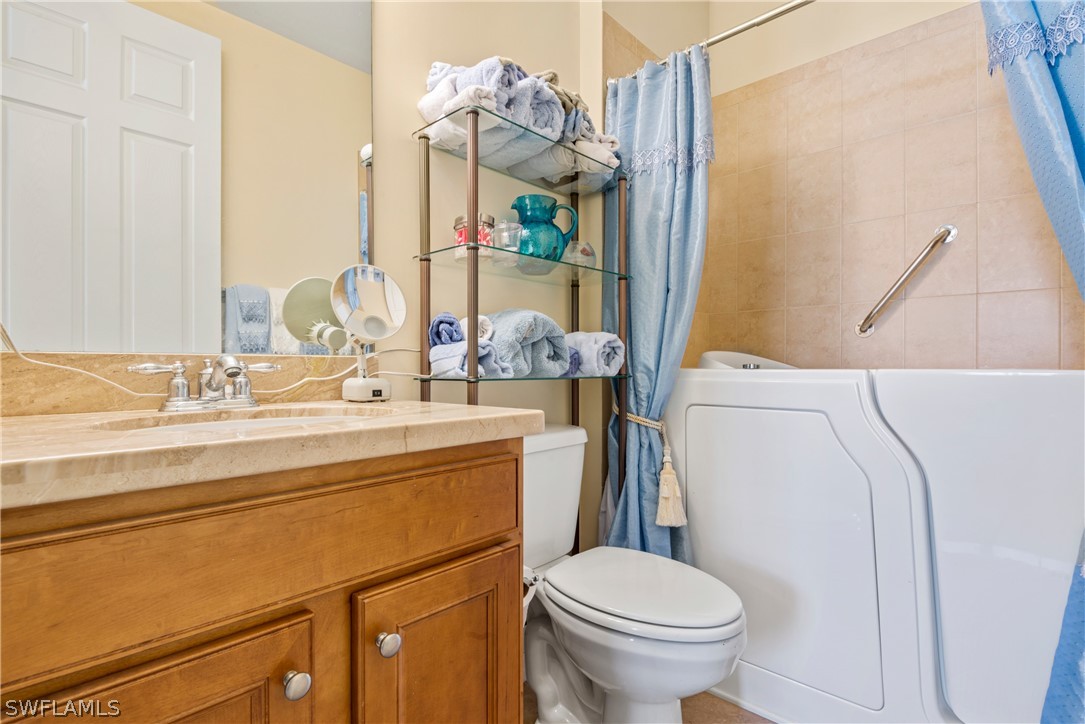 1387 Santiago Circle, Unit 802 Naples, FL 34113 - Photo 25 of 29 a bathroom with a sink a toilet and a mirror