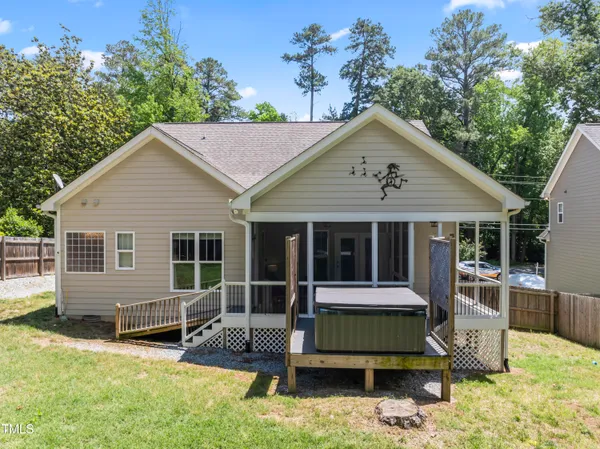 a view of house with yard outdoor seating and covered with trees in the background
