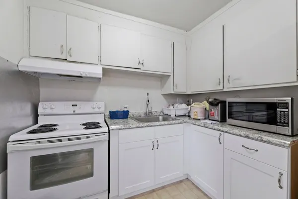 a kitchen with granite countertop white cabinets and white appliances