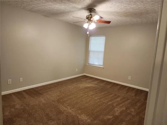 an empty room with a chandelier fan and windows