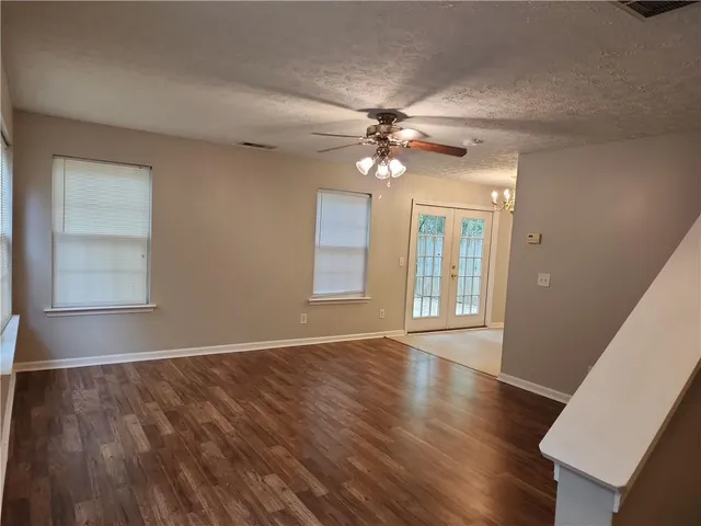 a view of an empty room with window and wooden floor