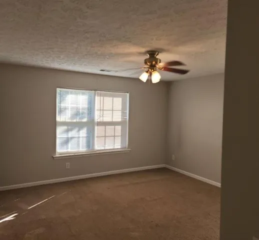 an empty room with windows and fan