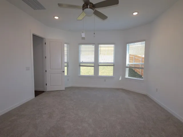 an empty room with a window and a ceiling fan
