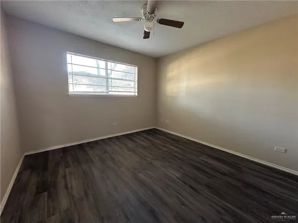 an empty room with wooden floor chandelier fan and windows