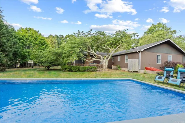 a view of pool with lawn chairs and plants