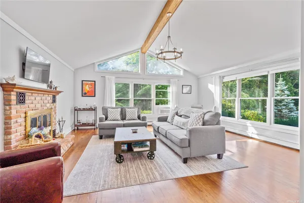 a living room with furniture large window and wooden floor