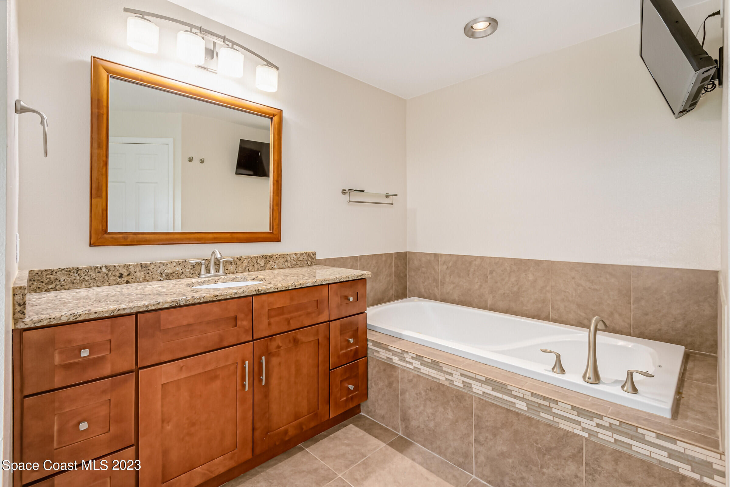 4181 Long Leaf Drive Melbourne, FL 32940 - Photo 23 of 37 a bathroom with a tub a double vanity sink and mirror