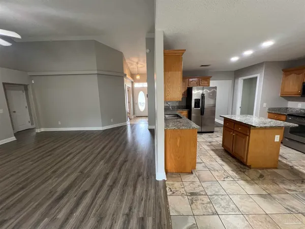 an open kitchen with kitchen island cabinets and refrigerator
