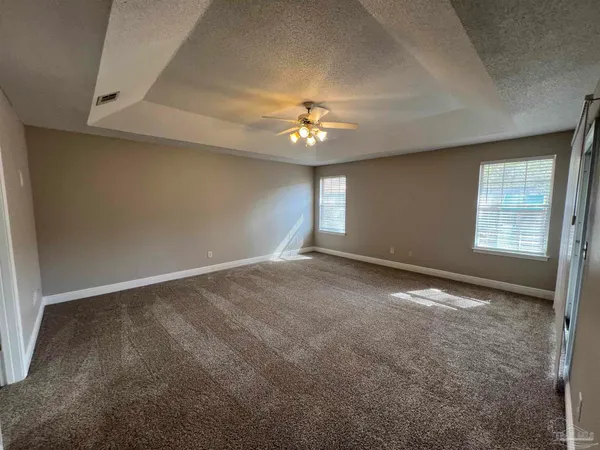 an empty room with windows and chandelier fan