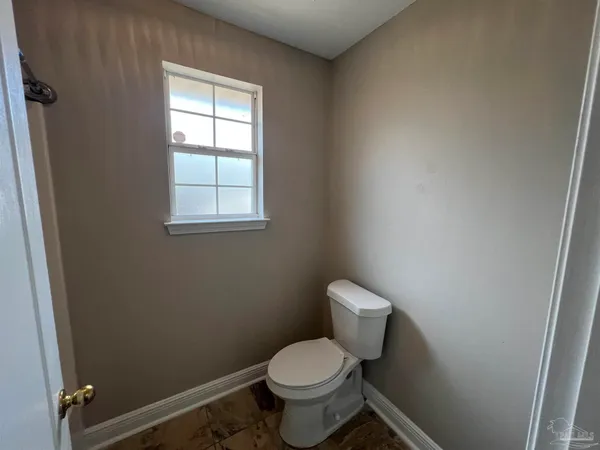 a white toilet sitting in a bathroom next to a window