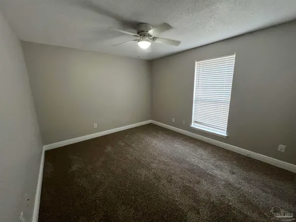 an empty room with a chandelier fan and windows