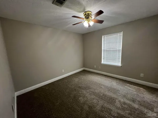 an empty room with a chandelier fan and windows