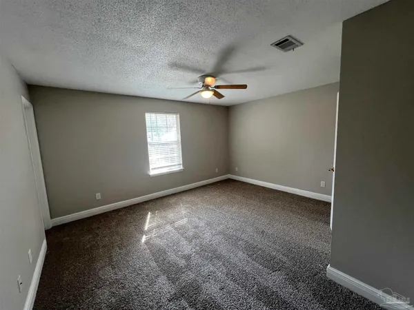 an empty room with windows and ceiling fan