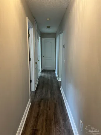 a view of a hallway with wooden floor and a bathroom