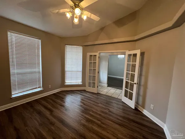 an empty room with wooden floor and windows