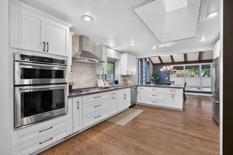 a kitchen with stainless steel appliances granite countertop a stove and white cabinets