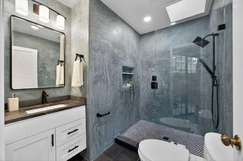 a bathroom with a granite countertop sink toilet and shower