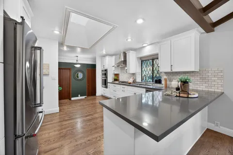 a kitchen with stainless steel appliances granite countertop a sink refrigerator and cabinets
