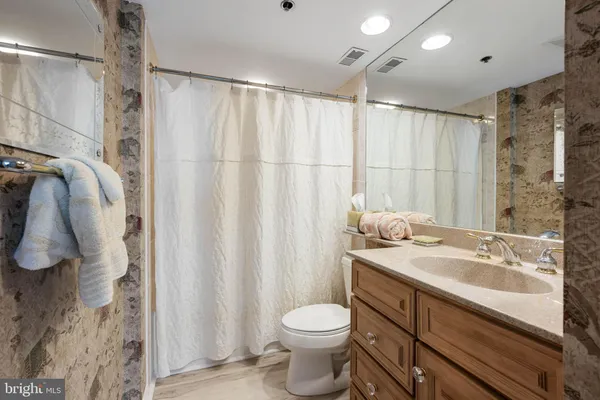 a bathroom with a shower sink vanity mirror and toilet