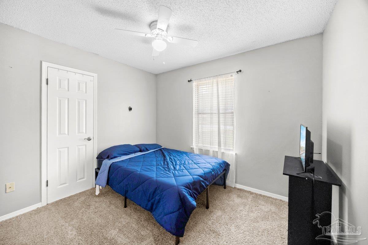 2194 Pompano Street Cantonment, FL 32533 - Photo 11 of 23 a spacious bedroom with a bed and a chandelier