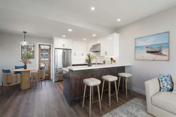 a kitchen with stainless steel appliances granite countertop a table chairs sink and white cabinets