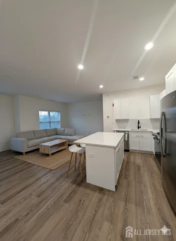 a large white room with kitchen island a stove a sink and a refrigerator