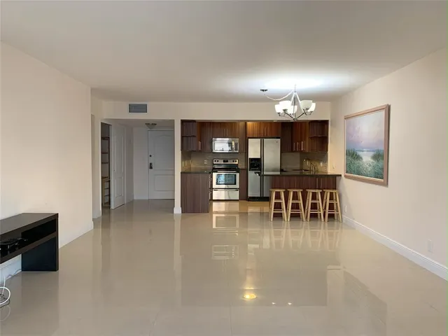 a kitchen with stainless steel appliances a dining table chairs and a refrigerator