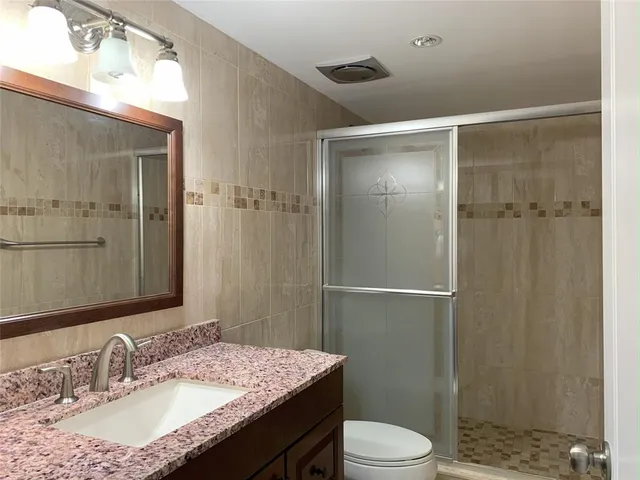 a bathroom with a granite countertop sink toilet and shower