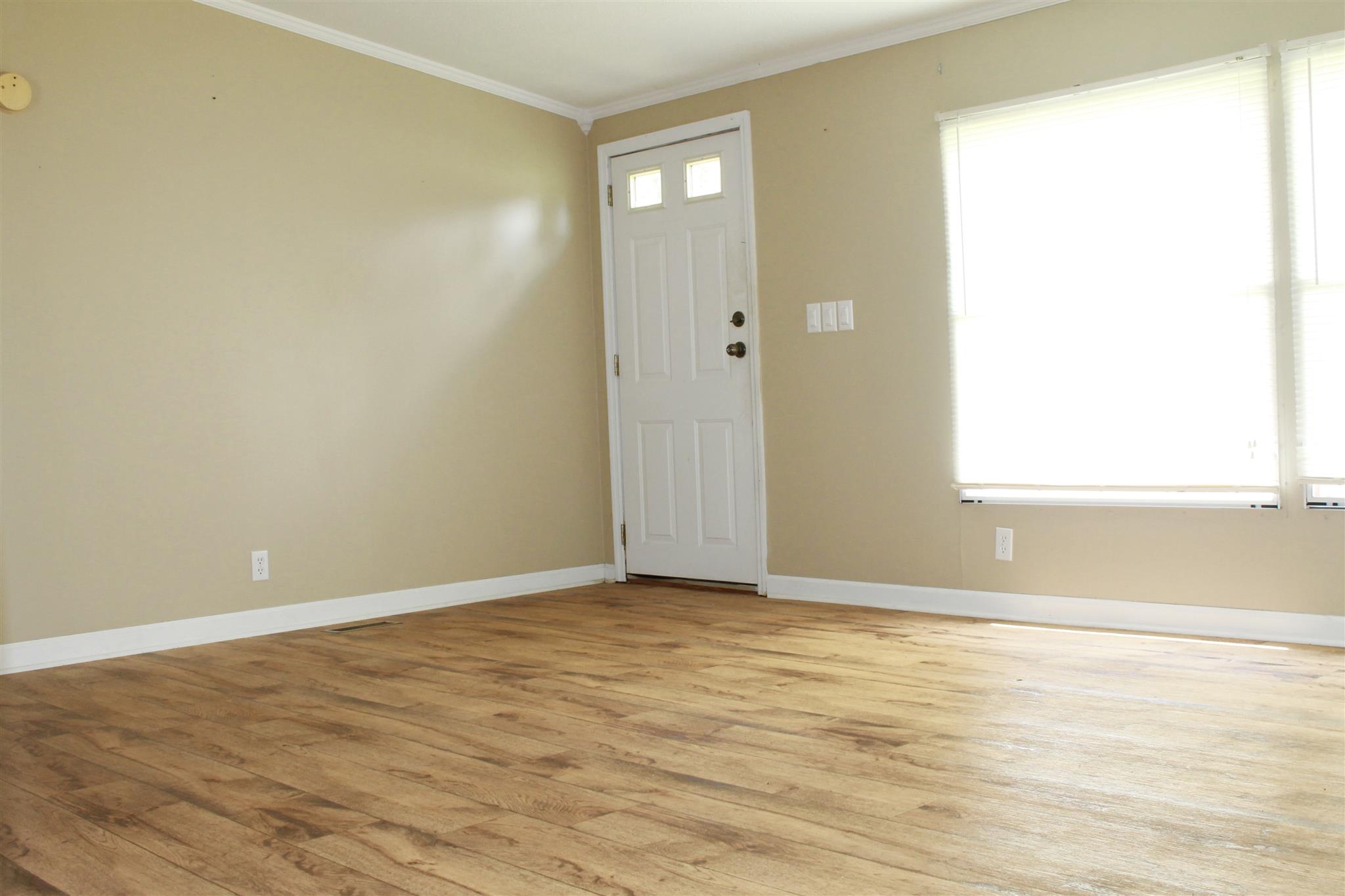 297 Longbranch Road Hohenwald, TN 38462 - Photo 5 of 13 LIVING ROOM WITH CROWN MOLDING, LAMINATE FLOORS AND LARGE PICTURE WINDOW