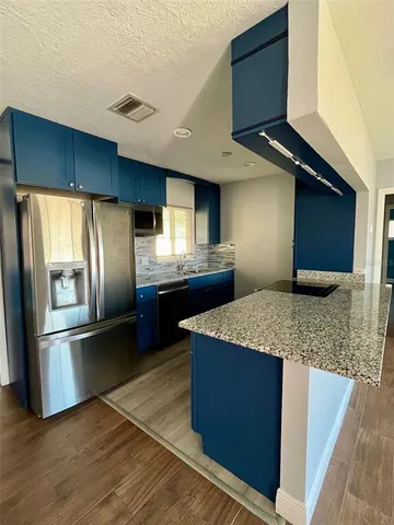 a kitchen with stainless steel appliances granite countertop a refrigerator a sink and wooden cabinets