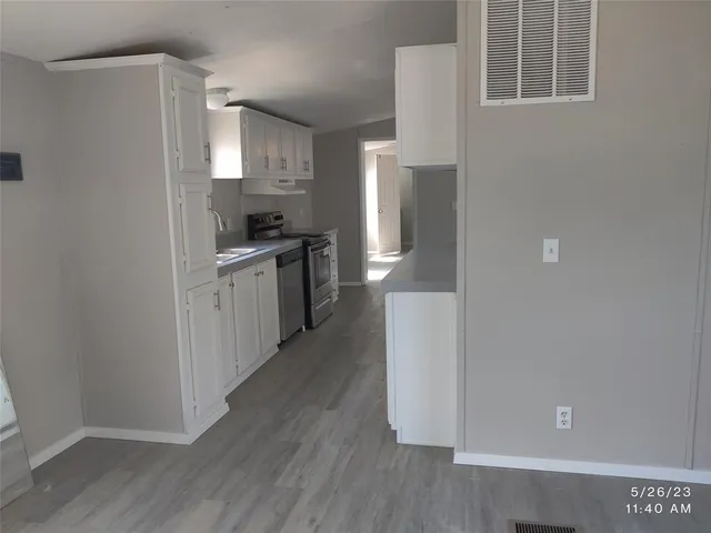 a kitchen with stainless steel appliances granite countertop a refrigerator a sink a stove and white cabinets with wooden floor