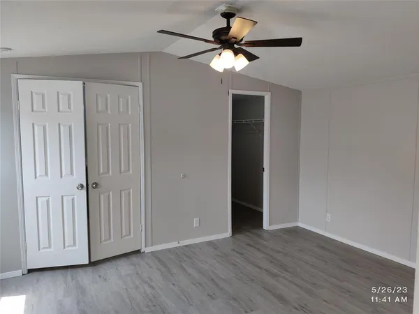 an empty room with wooden floor fan and windows
