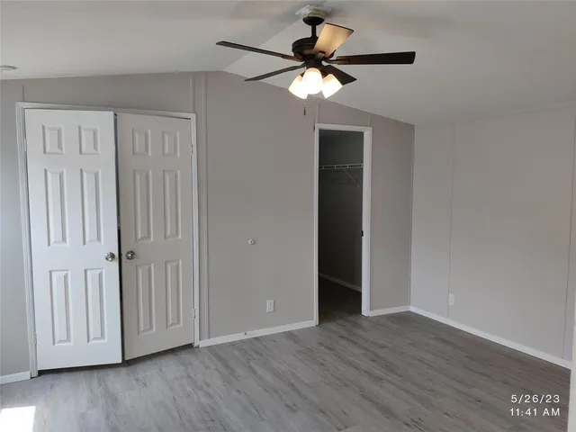 an empty room with wooden floor fan and windows