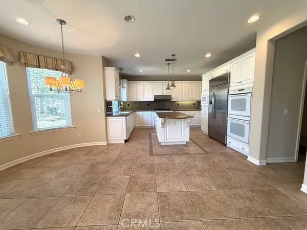 a kitchen with stainless steel appliances kitchen island granite countertop a refrigerator and a sink