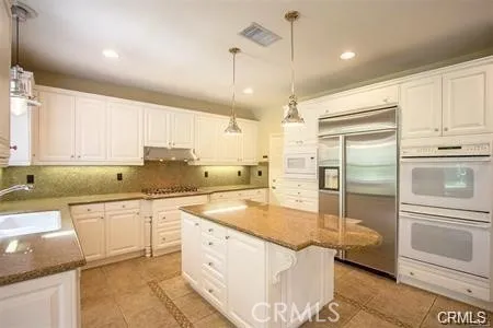 a kitchen with stainless steel appliances granite countertop a sink a stove and a refrigerator