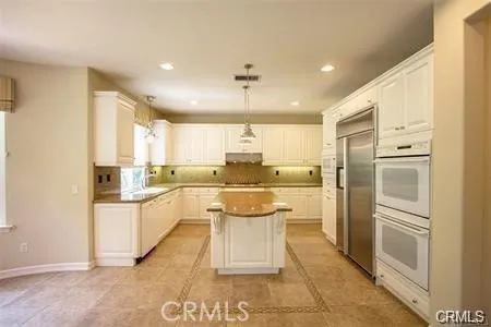 a kitchen with a refrigerator and white cabinets