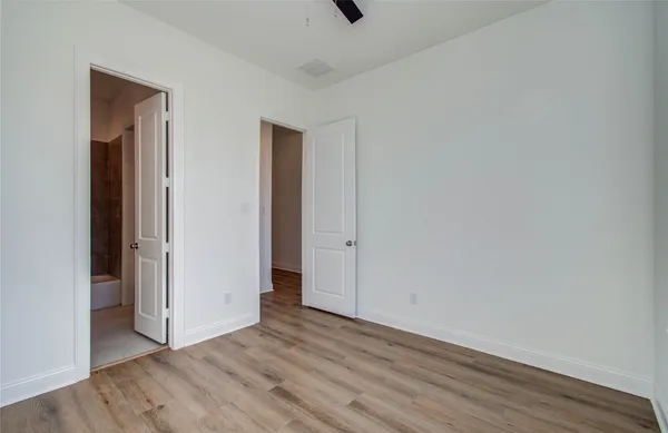 a view of an empty room with wooden floor and closet