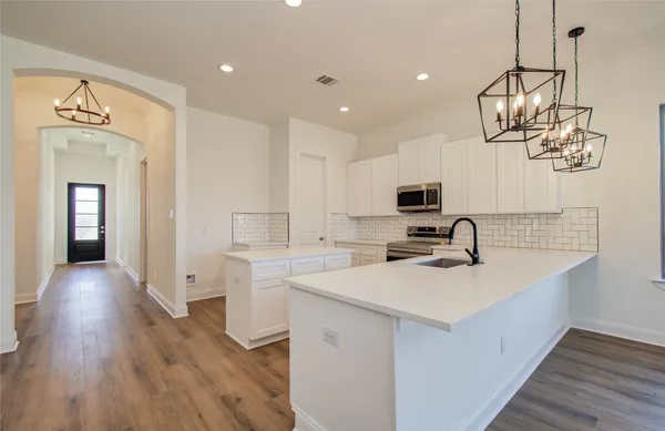 a kitchen with a sink dishwasher a stove and a microwave oven with wooden floor
