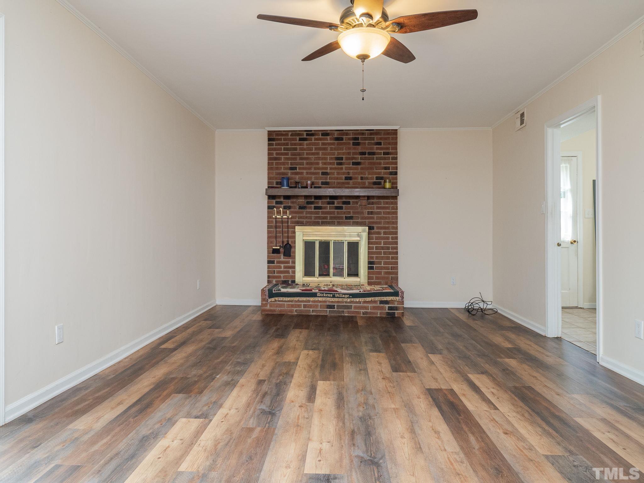 4504 Waterbury Road Raleigh, NC 27604 - Photo 10 of 38 an empty room with a fireplace and chandelier fan