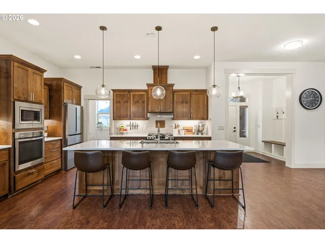 a kitchen with stainless steel appliances kitchen island granite countertop a table chairs and a refrigerator