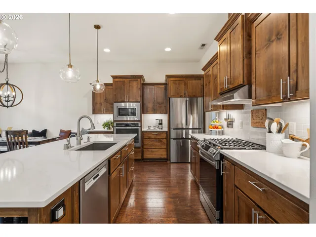 a kitchen with stainless steel appliances granite countertop a sink a stove and a refrigerator