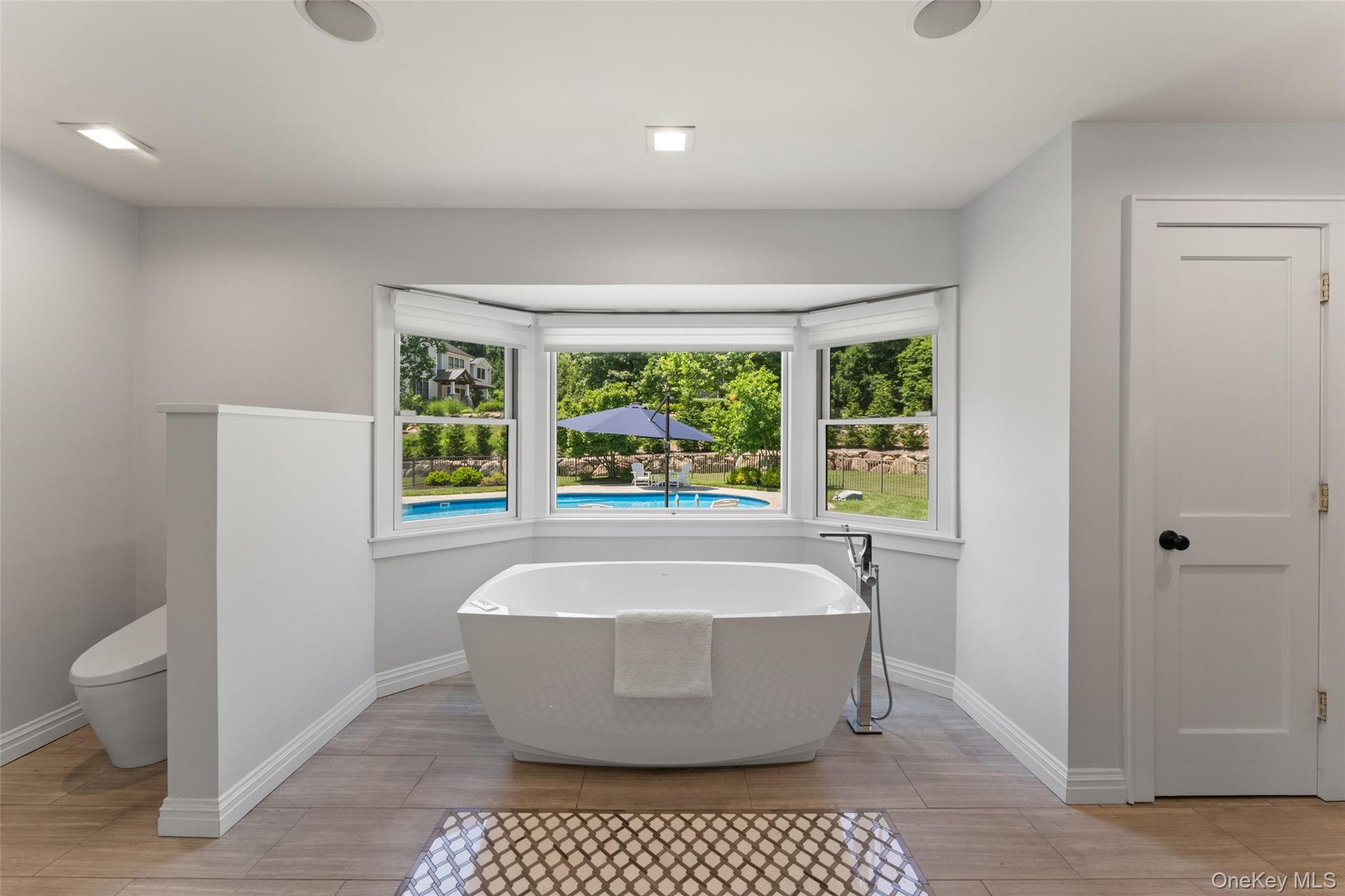 211 Strawtown Road West Nyack, NY 10994 - Photo 19 of 47 Primary ensuite spa-like bath featuring a soaking tub with a view of the pool, steam shower, double vanities, and radiant heated flooring.