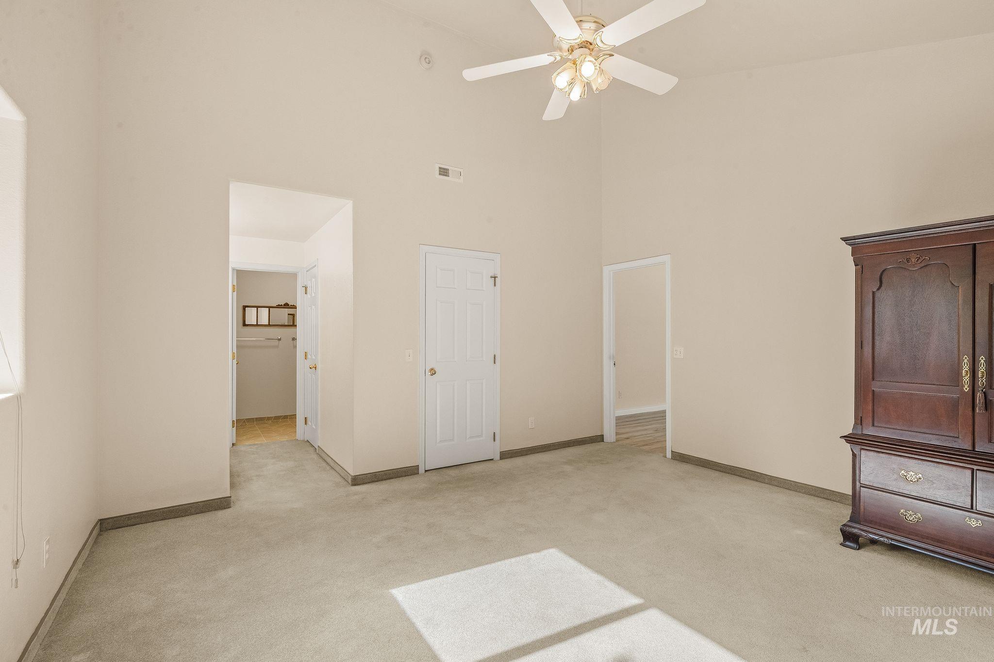 1091 Cedar Ridge Road Kendrick, ID 83537 - Photo 39 of 48 Carpeted interior space featuring a vaulted ceiling with a ceiling fan light fixture, beige wall paint, white trim, and a white interior door