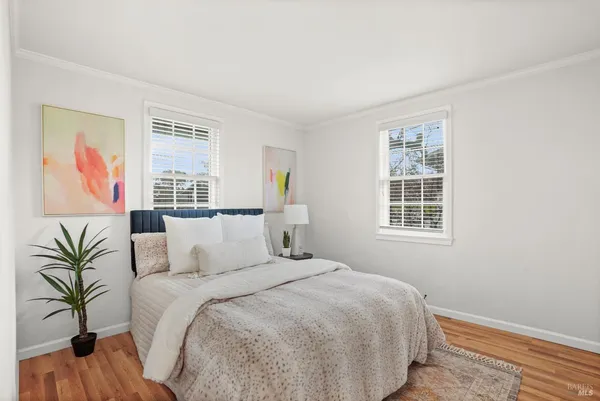 a large bed sitting in a bedroom next to a window and a wooden floor