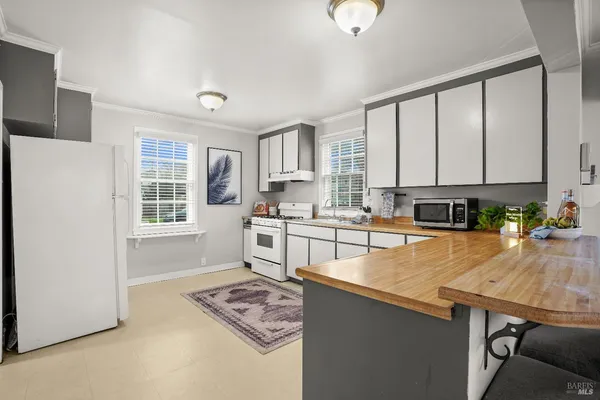 a kitchen with stainless steel appliances granite countertop a stove top oven a sink dishwasher and white cabinets with wooden floor