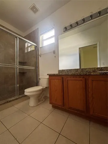 a bathroom with a granite countertop sink a toilet and a mirror