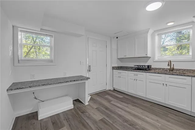 a kitchen with granite countertop white cabinets and wooden floor