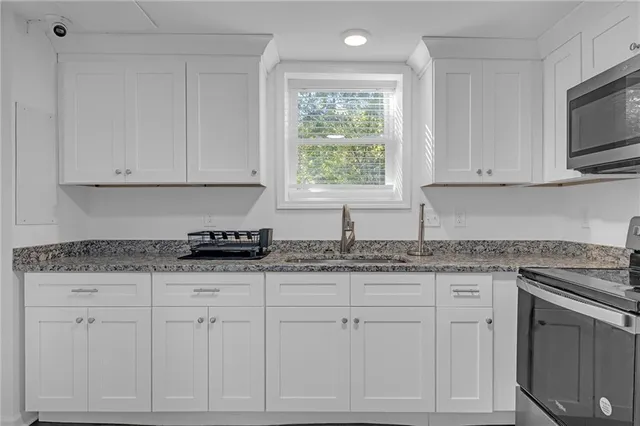 a kitchen with granite countertop white cabinets and sink